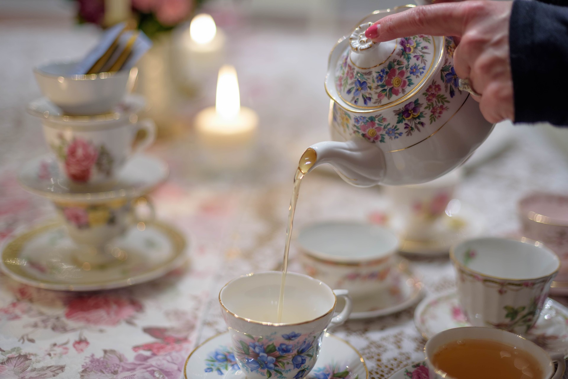 Closeup of woman pouring tea into vintage teacup